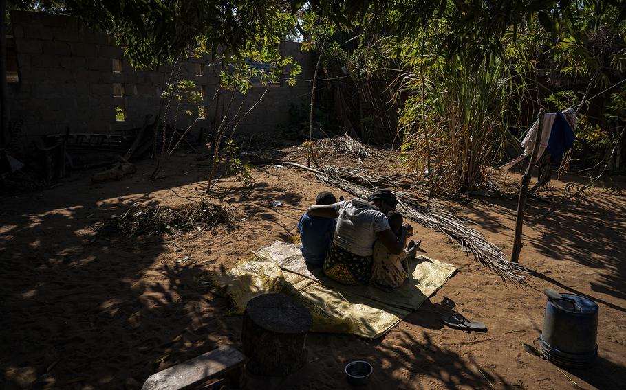 Ana sits near her home with two of her children in a village near Pemba, Mozambique, on Sept. 2, 2022.