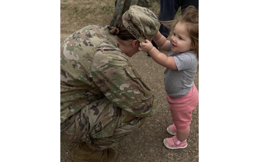 Jordan Donais, 1, reaches for the hat of her mother, Capt. Pam Donais, during a deployment ceremony at Fort Campbell, Ky. Donais and her husband Staff Sgt. Dan Donais are deployed to Europe with 1st Brigade Combat Team, 101st Airborne Division. 