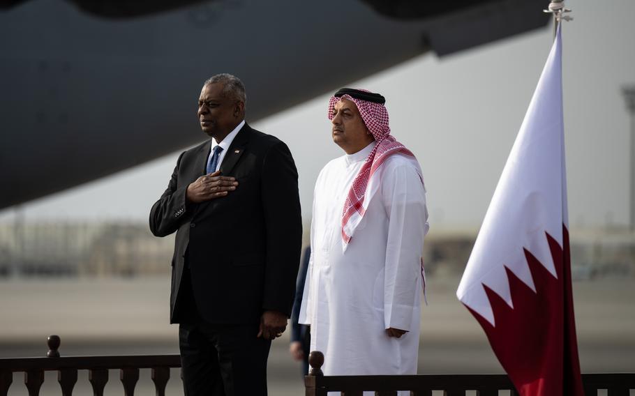 Defense Secretary Lloyd J. Austin III and Qatar Defense Minister Khaled Al Attiyah stand during the playing of the American national anthem at Al Udeid Air Base, Qatar, Dec. 19, 2023. The U.S. has reportedly reached a deal with Qatar to extend its military presence at Al Udeid for another 10 years.