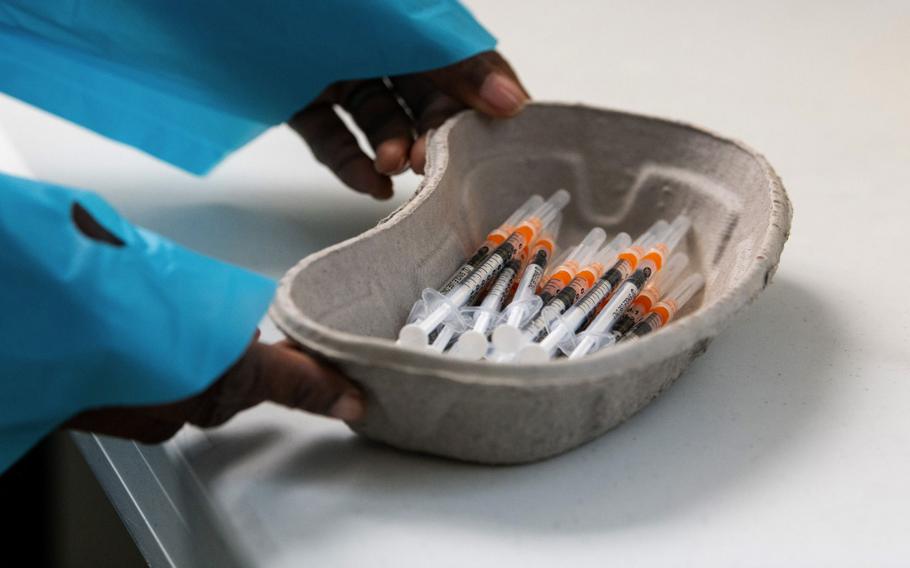 A health care worker places a dish of syringes near a vial of COVID-19 vaccine, produced by Pfizer and BioNTech, at a vaccination center in a town hall in Paris on April 9, 2021.