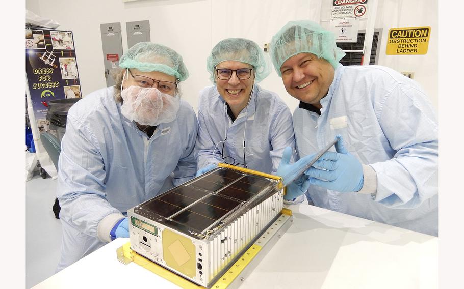 Wesley Faler, Don Smith and Alex Wingeier with the miniature satellite known as a CubeSat that they built. It will hitch a ride onboard NASA’s Artemis 1 and then propel itself into deep space. 