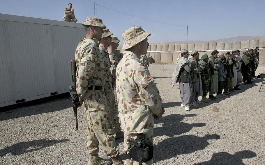 In this Feb. 17, 2007 file, Australian soldiers, part of the International Security Assistance Force (ISAF), stand near local Afghans at a ceremony to open a Trade Training School, funded by Australian forces at the Tarin Kowt military base in Uruzgan province, south of Kabul, Afghanistan.