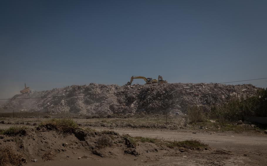 A dump truck and excavators sort through mass piles of rubble in Samandag.