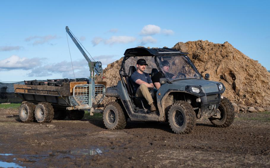Army Spc. Taven Kimmel, left, and Army Sgt. Dustin Mattern, both with the 2nd Cavalry Regiment, move buckets of soil extracted from a pit in Wistedt, Germany, to a nearby area Oct. 30, 2023. The soil will be examined for airplane debris and possible human remains.