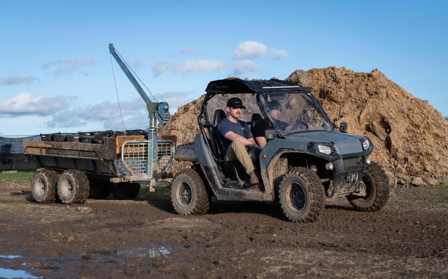 Army Spc. Taven Kimmel, left, and Army Sgt. Dustin Mattern, both with the 2nd Cavalry Regiment, move buckets of soil extracted from a pit in Wistedt, Germany, to a nearby area Oct. 30, 2023. The soil will be examined for airplane debris and possible human remains.