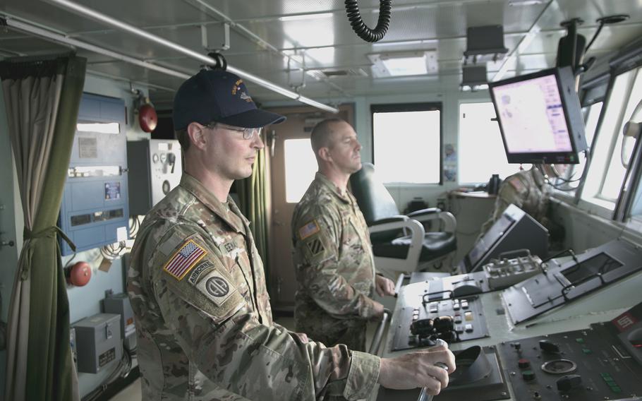 Chief Warrant Officer 2 Sean Meenan, left, steers the USAV Fort McHenry off the coast of Okinawa on Nov. 10, 2021.