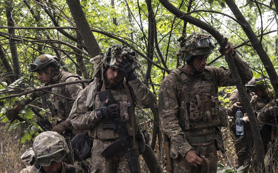 Fearing they spotted a Russian drone overhead, fighters of the Ukrainian Territorial Defense take cover on June 21, 2022, in woods along a road that leads to Lysychansk, Ukraine. 