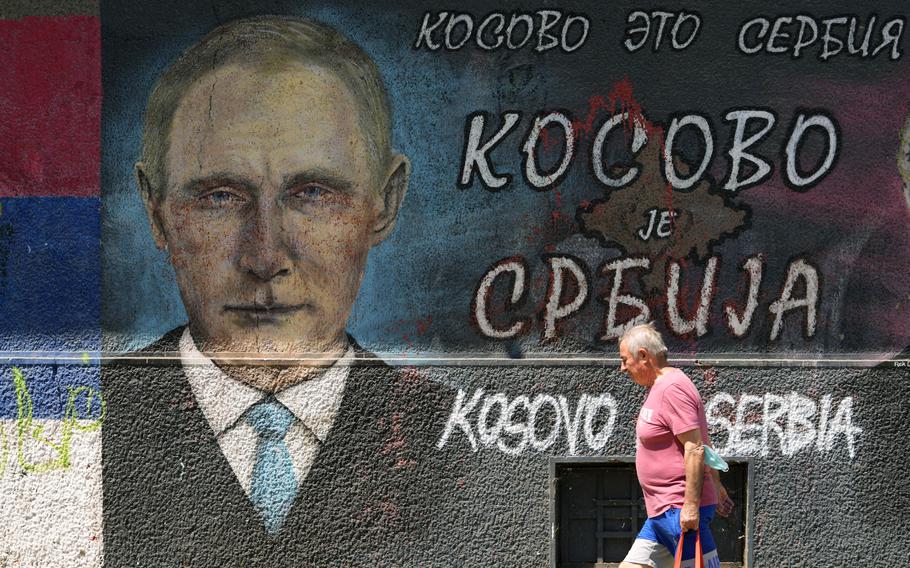 A man passes by graffiti depicting Russian President Vladimir Putin, reading: "Kosovo is Serbia" in Belgrade, Serbia, Monday, Aug. 1, 2022. Kosovo's authorities early Monday moved to ease mounting ethnic tensions in the country by delaying a controversial order on vehicle license plates and identity cards that triggered riots by minority Serbs who put up roadblocks, sounded air raid sirens and fired their guns into the air. 