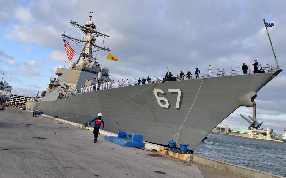 Sailors stand along the rails as the ship arrives portside.