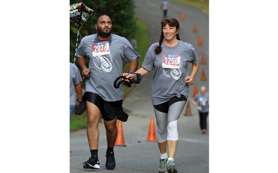 Gaston College Officer Crystal Todd helps lead blind Gaston College Alum, Angus Kola, during the inaugural Stampede for Student Success 5K Run held Oct. 2, 2021, on the campus of Gaston College in Dallas, N.C.