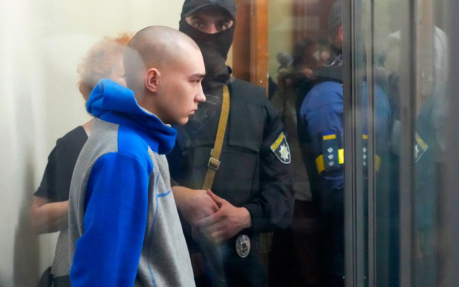 Russian army Sergeant Vadim Shishimarin, 21, is seen behind a glass during a court hearing in Kyiv, Ukraine, Friday, May 13, 2022. The trial of a Russian soldier accused of killing a Ukrainian civilian opened Friday, the first war crimes trial since Moscow's invasion of its neighbor.