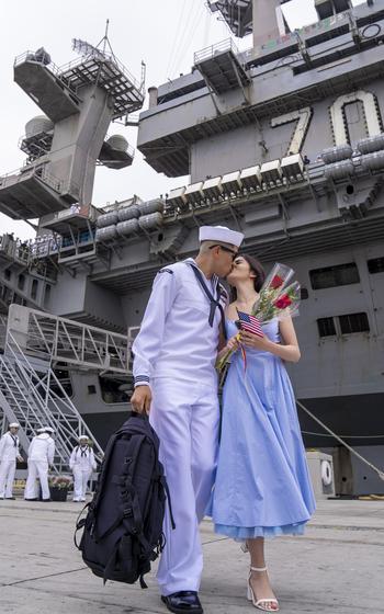 A sailor and a woman share a kiss.