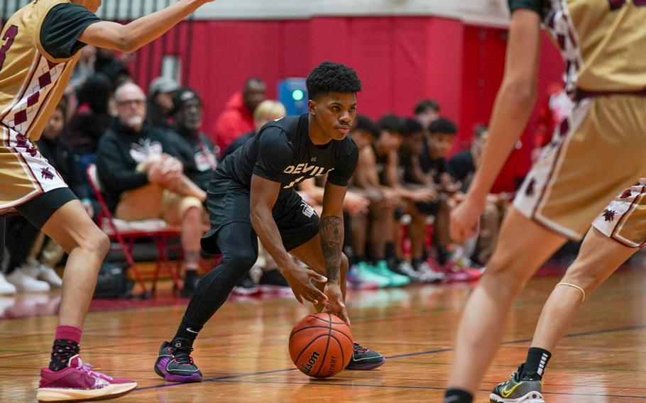 Nile C. Kinnick's Xavier Wright looks for room between two Matthew C. Perry defenders during Friday's DODEA-Japan boys basketball game. The Red Devils won 87-53.