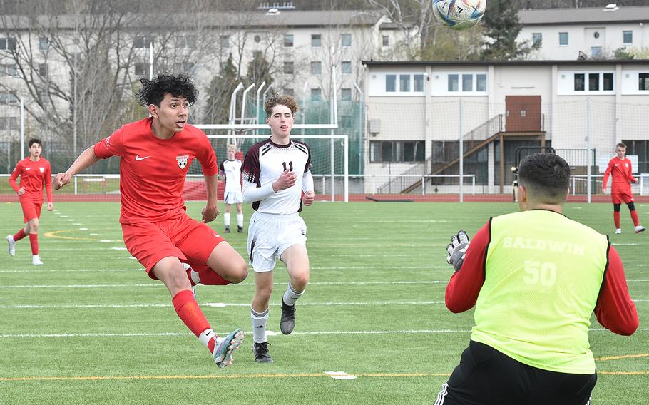Kaiserslautern’s Antonio Robles, left, chips the ball over Vilseck goalkeeper Jayson Baldwin during the second half of Saturday afternoon’s match at Kaiserslautern High School in Kaiserslautern, Germany. Trailing the play is, center left, the Falcons’ David Henderson.