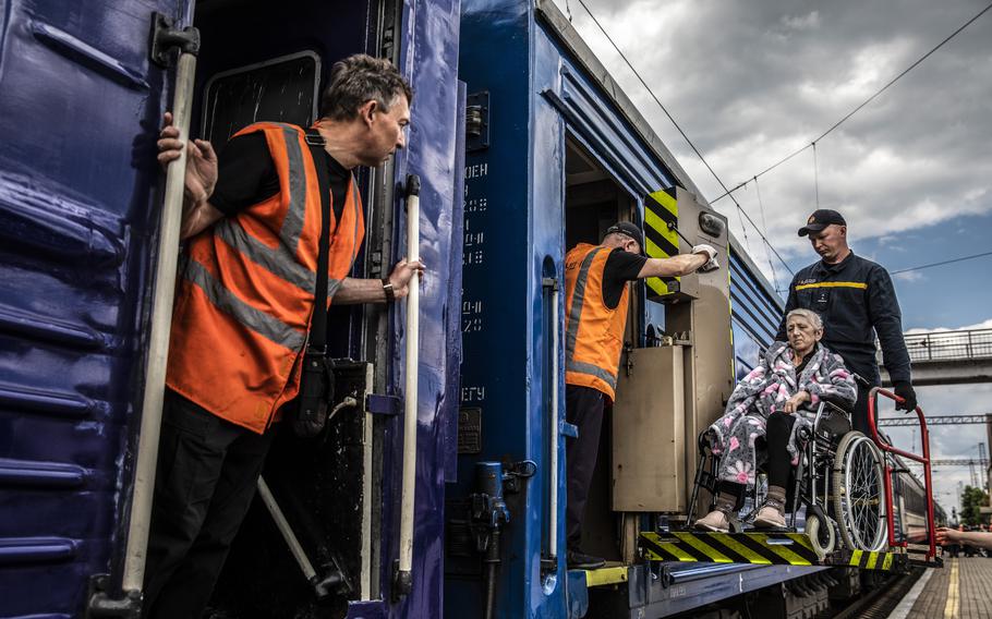 A disabled elderly woman in a wheelchair is lifted onto an evacuation train in Pokrovsk. 