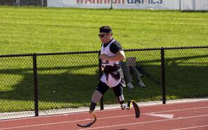 A man with prosthetic legs runs down a track.