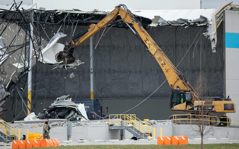 Crews use an excavator to pull down pieces of a damaged roof during search and rescue operations at the Amazon distribution center in Eadwardsville, Ill., on Saturday, Dec. 11, 2021, after overnight severe storms caused the building to partially collapse.