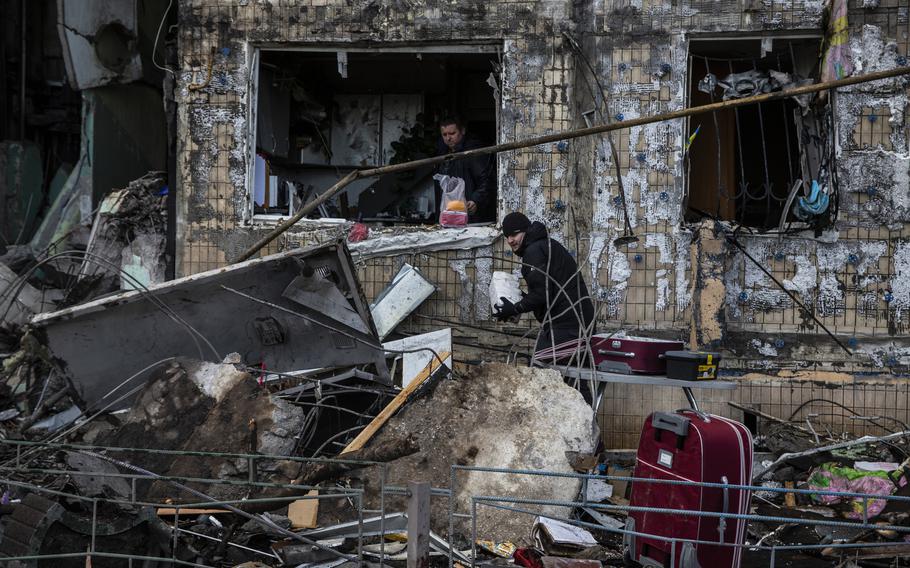 People retrieve belongings from a destroyed residential apartment block, in the northwestern Obolon district of Kyiv on March 14, 2022. 