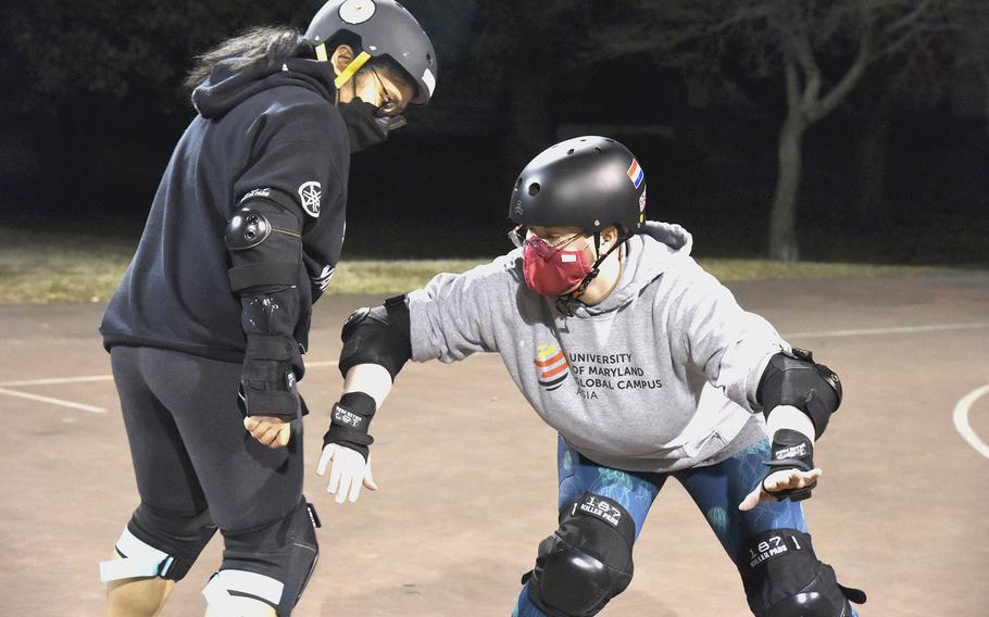 Coach Hannah Howard of the Fuji Flatliners and the Killer Katanas, right, teaches Staff Sgt. Vanessa Seay of the  Flatliners how to block during practice at Yokota Air Base, Japan, on Feb. 28, 2022. 