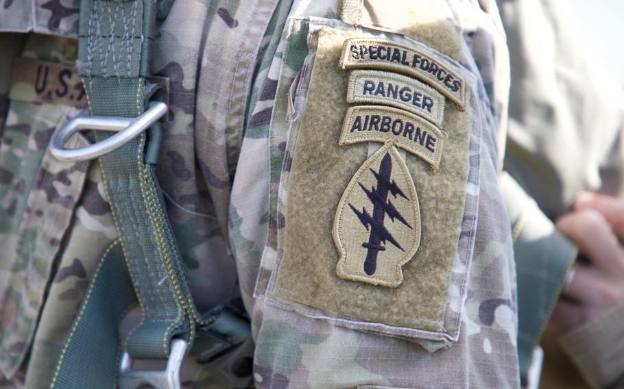 An Army Green Beret, assigned to 20th Special Forces Group, Alabama National Guard, displays a unit patch and tabs while being rigged up into a MC-6 parachute at Northeast Alabama Regional Airport in 2019. 