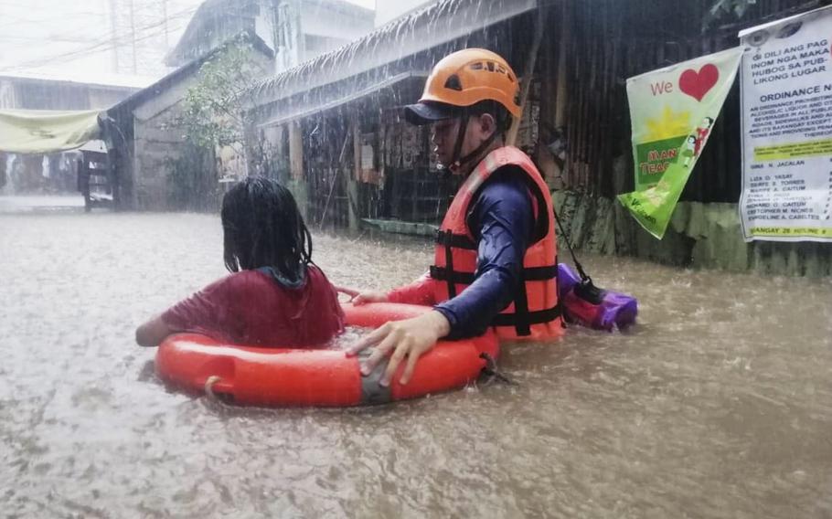A rescuer assists a girl as they wade through flooding caused by Typhoon Rai in Cagayan de Oro City, southern Philippines on Thursday, Dec. 16, 2021. 