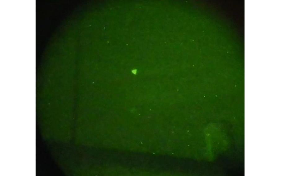 This is a Navy image of an unidentified aerial phenomena captured during naval exercises off the East Coast of the United States in early 2022. The image was captured through night vision goggles and a single lens reflex camera. Based on additional information and data from other sightings, the UAP in this image were subsequently reclassified as unmanned aerial systems.