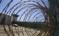 FILE - In this Wednesday, April 17, 2019 file photo reviewed by U.S. military officials, the control tower is seen through the razor wire inside the Camp VI detention facility in Guantanamo Bay Naval Base, Cuba. The Biden administration has transferred a detainee out of the Guantánamo Bay detention facility for the first time, sending a Moroccan man back home years after he was recommended for discharge. (AP Photo/Alex Brandon, File)