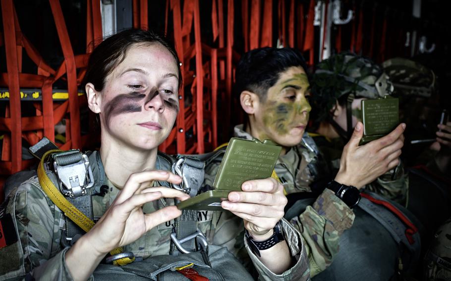 Two U.S. Army paratroopers apply camouflage to their faces March 14, 2024, during the 173rd Airborne Brigade's all-female parachute jump near Vajont, Italy.