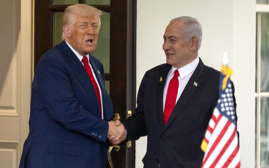 Trump and Netanyahu shaking hands with Trump mid-sentence and Netanyahu smiling as he looks at Trump.