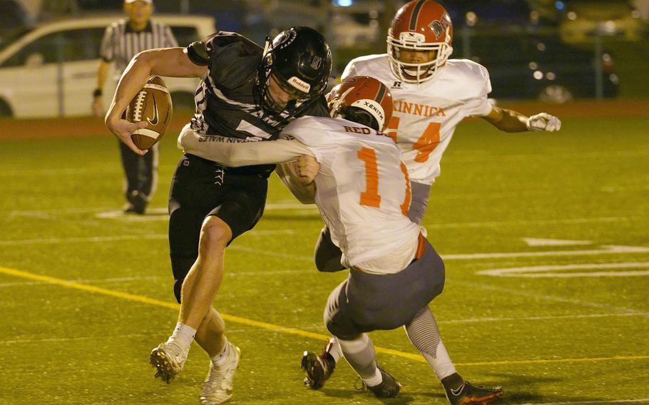 Zama starting quarterback Dominic Peruccio gets hemmed in by Nile C. Kinnick's Michael Lozano and Ryo Nishiyama.