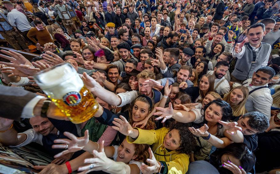 Young people reach out for free beer in one of the beer tents on the opening day of the 187th Oktoberfest beer festival in Munich, Germany, Saturday, Sept. 17, 2022. Oktoberfest is back in Germany after two years of pandemic cancellations.
