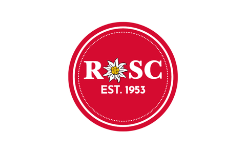 Photo Of The letters ROSC and EST. 1953 in white on a red circle. The “O” in the ROSC is replaced with a white dandelion.