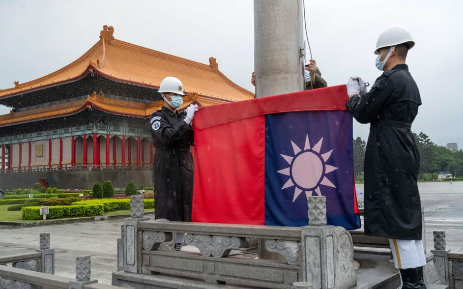 Honor guards wearing protective masks raise a Taiwanese flag at the National Chiang Kai-shek Memorial Hall in Taipei, Taiwan.