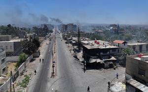 A view of a large street with buildings lining either side, some of which are smoking.