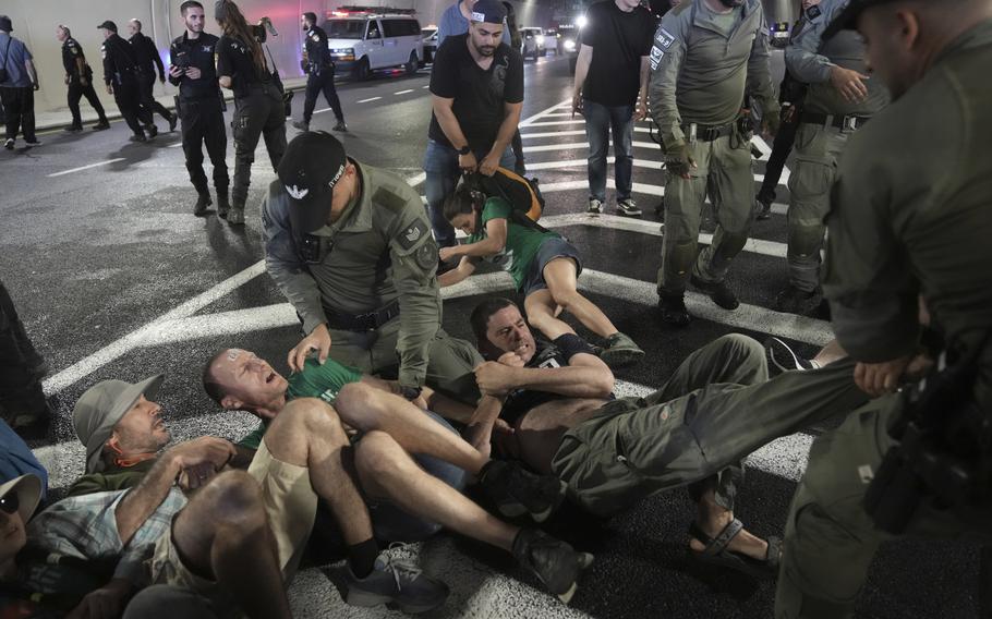 Police try to contain a group of protesters, lying on the ground,
