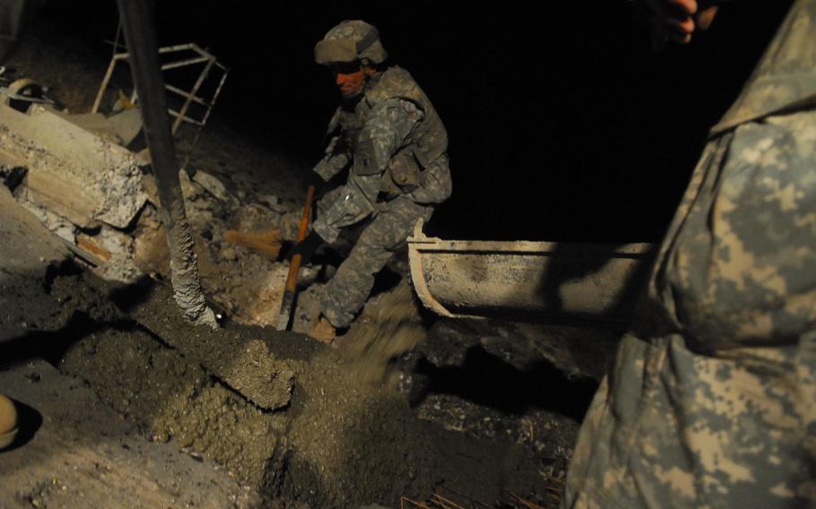 Soldiers with the 19th Engineer Battalion spread concrete in a fresh roadside bomb crater near Tikrit, Iraq. If left unrepaired, the craters provide hiding places for explosives and driving hazards for motor vehicles.