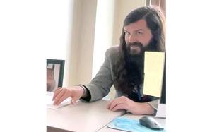 A man with long hair at a desk.