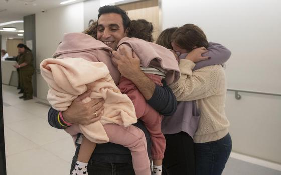 Aviv Asher, 2, 5-year-old, her sister Raz Asher, 4,5-year-old, and mother Doron, react as they meet with Yoni, Doron's husband and their father, after they returned to Israel to the designated complex at the Schneider Children's Medical Center on Friday, Nov. 24, 2023.  A four-day cease-fire in the Israel-Hamas war began in Gaza on Friday with an exchange of hostages and prisoners.