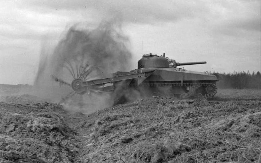 A black and white photo of a tank equiped with flails used to disarm mines