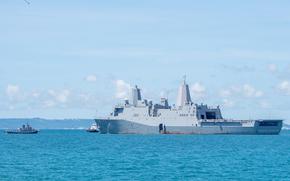 The USS New Orleans anchored with two smaller vessels are alongside in the water.