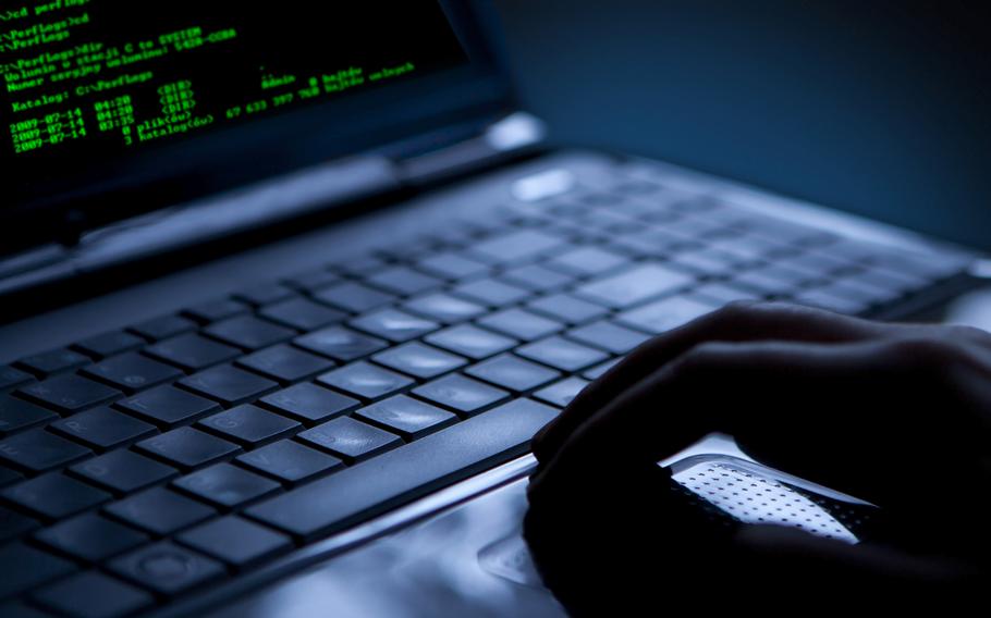 A close-up view of a hand using a laptop computer with green text on the screen.