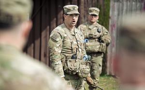 A US Army Captain speaks to a group of soldiers who are standing around him.
