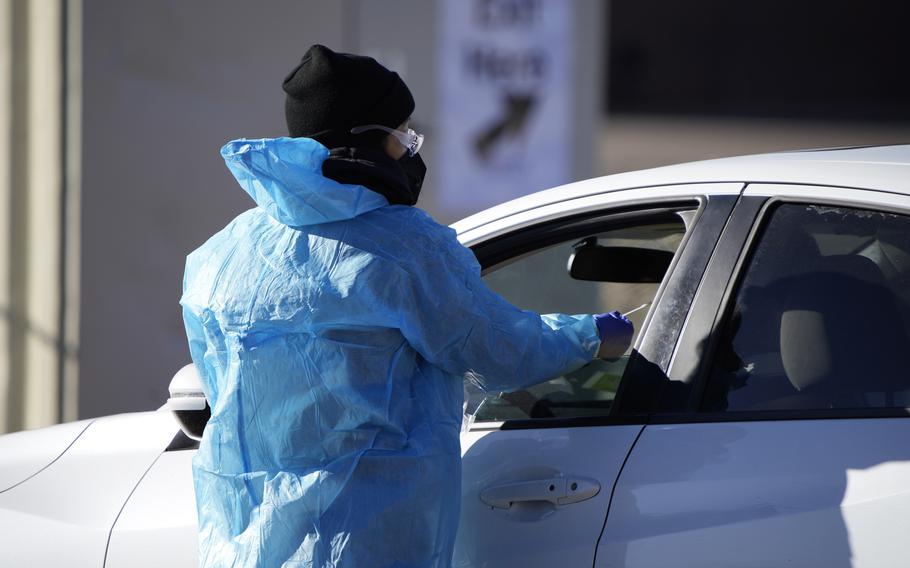 A medical technician performs a nasal swab test on a motorist queued up in a line at a COVID-19 testing site near All City Stadium Dec. 30, 2021, in southeast Denver. Millions of workers whose jobs don’t provide paid sick days are having to choose between their health and their paycheck as the omicron variant of COVID-19 rages across the nation.