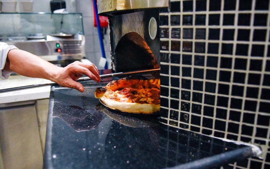 A pizza is pulled out of the oven.