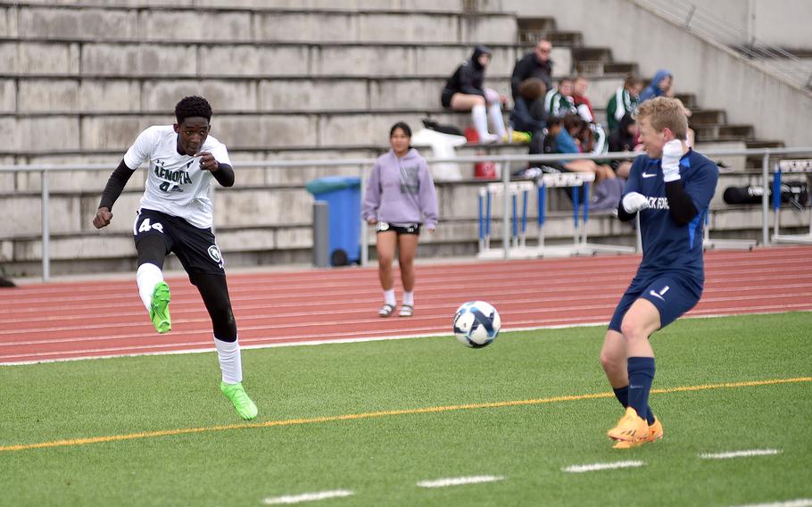 AFNORTH's Marc Kpade crosses the ball as Black Forest Academy's Jack Cox tries to block it during a match on April 20, 2024, at Ramstein High School on Ramstein Air Base, Germany.