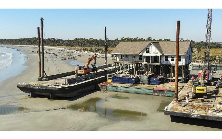 A worker looks out of an access cut into the gabled roof of USCB’s former maritime laboratory as work begins to remove the structure on Monday, Oct. 24, 2022 on Pritchards Island, South Carolina.