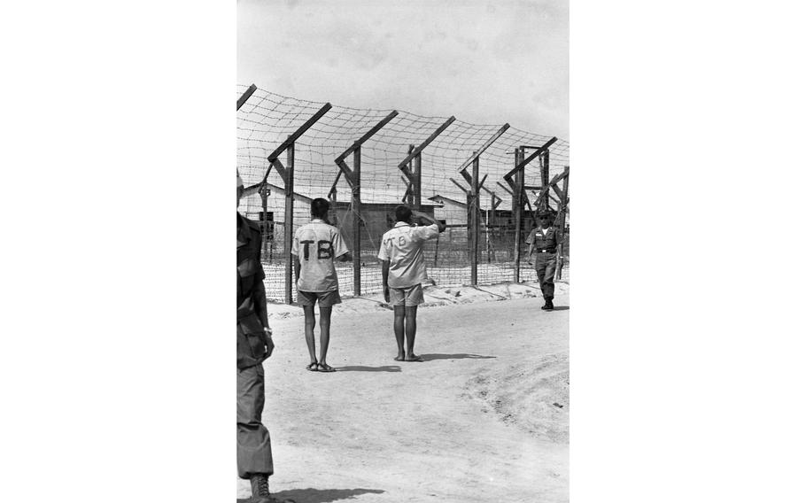 Viet Cong prisoners pass through the Bien Hoa prison camp. The prisoner of war camp is a compex of 55 buildings; barracks, kitchens, mess halls, libraries, and a dispensary with a doctor. 