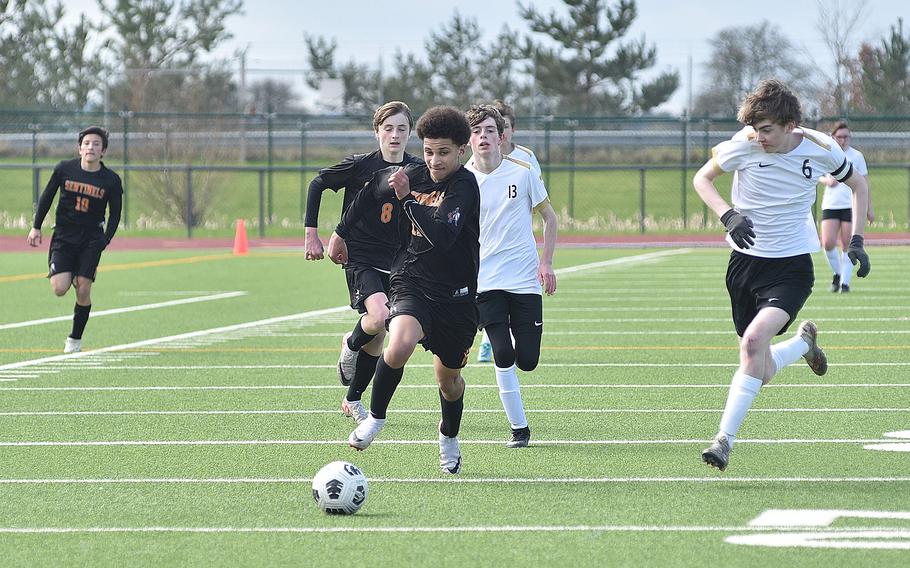Spangdahlem forward Jeremy White runs after a ball during a March 16, 2024, game against Alconbury at Spangdahlem High School in Spangdahlem, Germany. Dragon defender Aaron Dudley, right, chases after the ball and man.