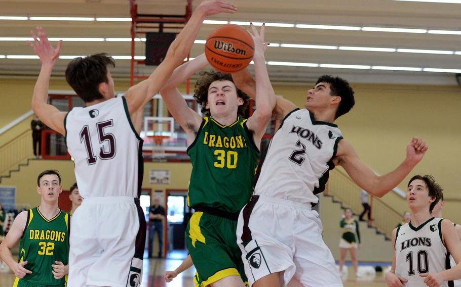 AFNORTH’s Nathan Goldsmith, left, and Ronnie Macauley stop Alconbury’s Bohdan Andre’s drive to the basket in a D-III game on opening day of the DODEA-Europe basketball finals in Baumholder, Germany, Feb. 15, 2023. The Lions beat the Dragons 66-47. 