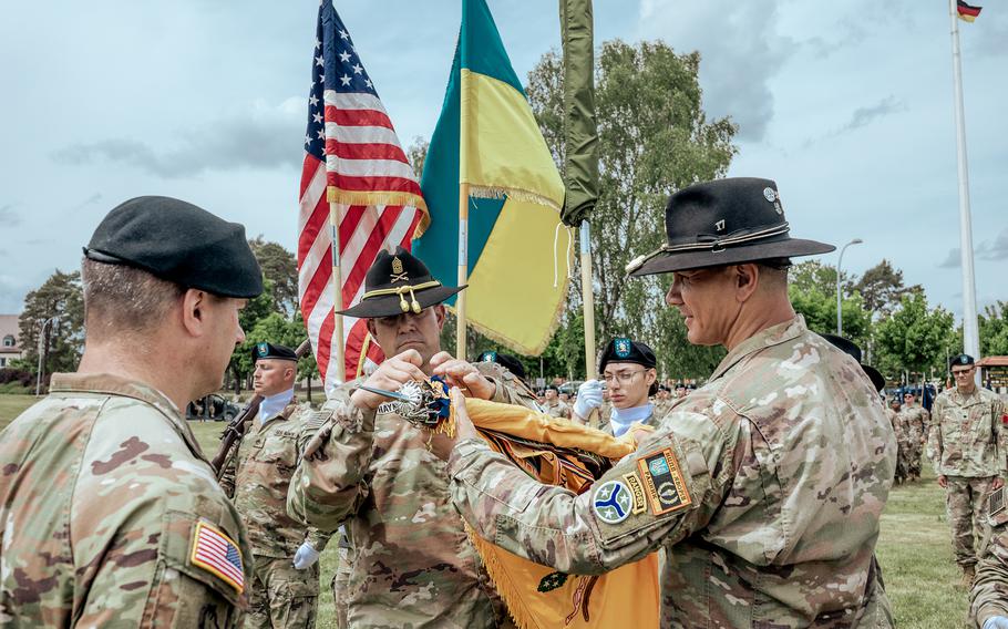Uniformed soldiers prepare a ceremonial flag.